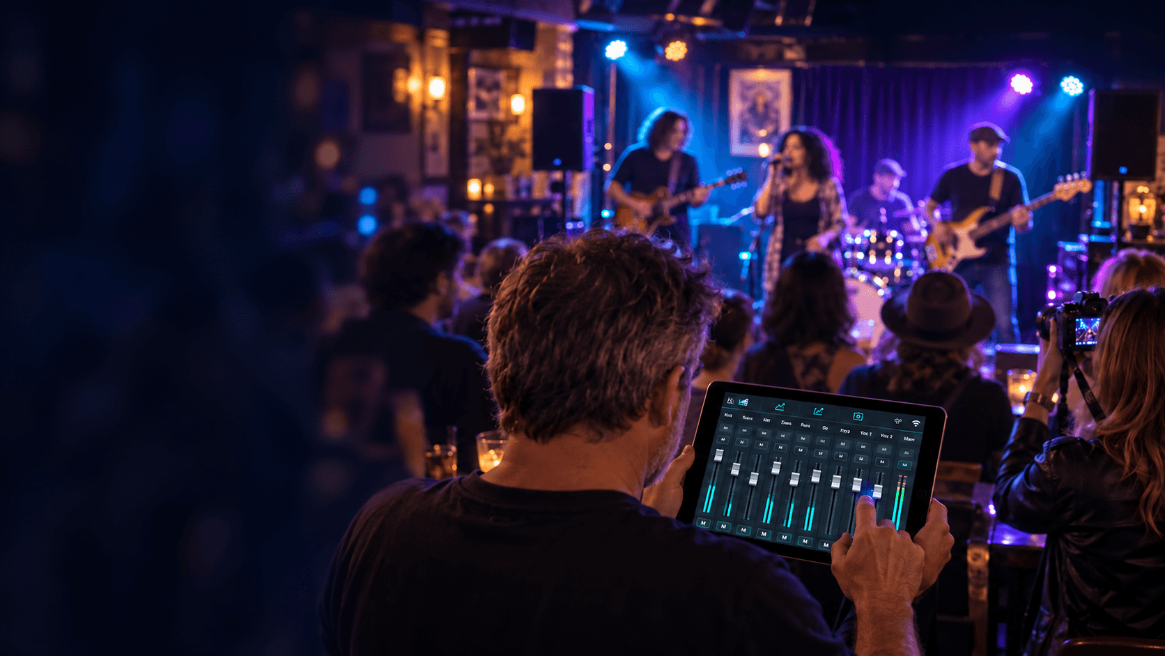 Live sound engineer using a tablet mixer beside a photographer at a gig